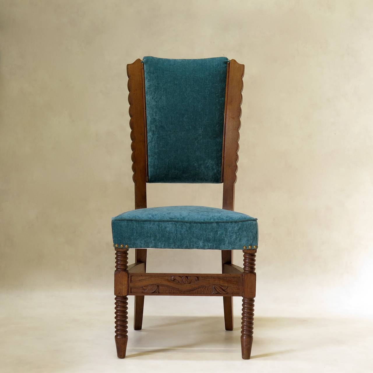 Unusual and elegant set of six dining chairs with carved wooden structures. Tapered backs with scalloped edges, extending down into sabre legs. Ringed front legs, joined by a carved stretcher. Newly upholstered in plush teal velvet.