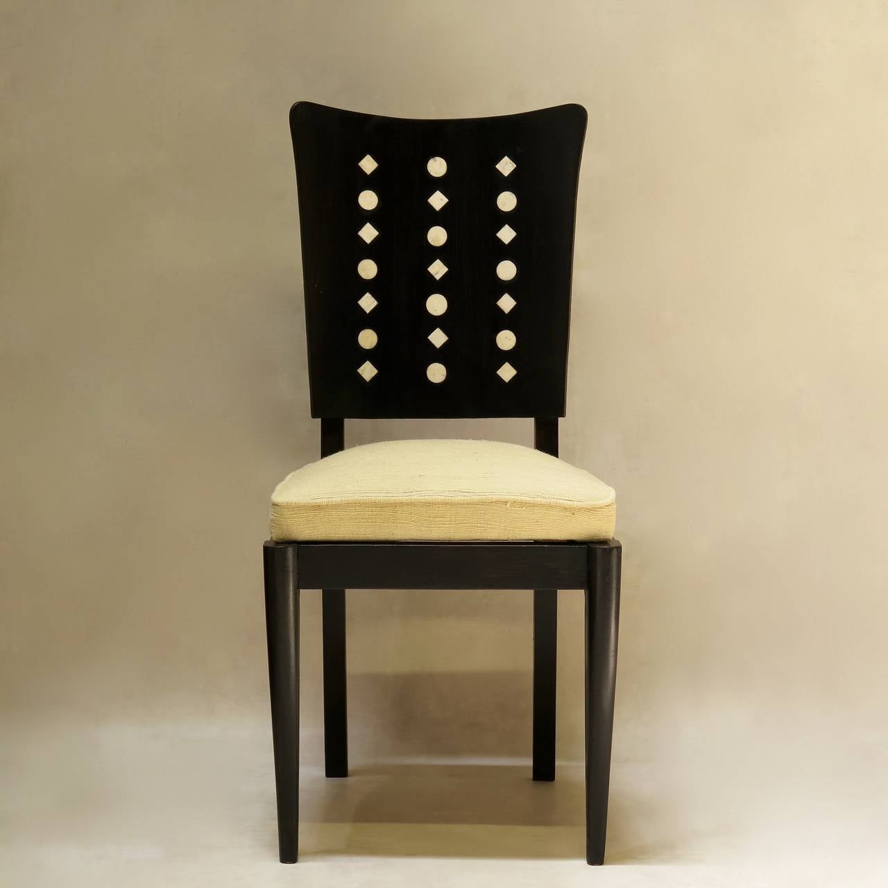Set of six Art Deco dining room chairs in ebonized wood with generous curved backs inlaid with a design of circles and lozenges. The seats have been newly upholstered with vintage, textured off-white fabric.