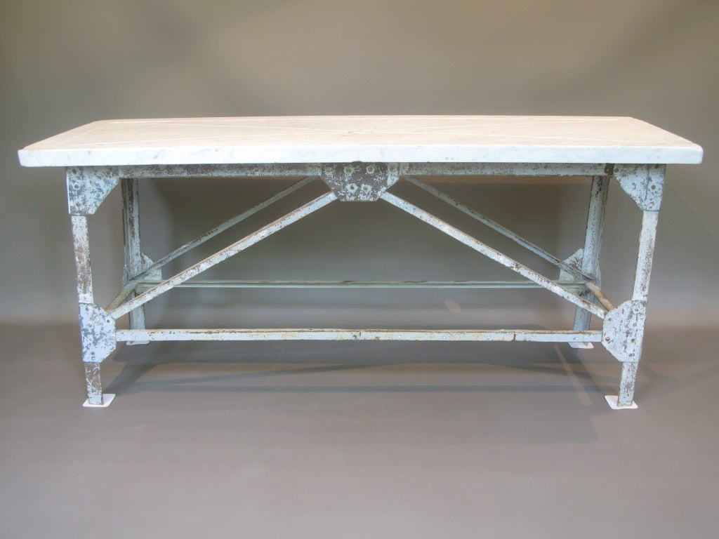 Authentic fishmonger's table. 

Hand wrought iron base assembled with rivets, and still bearing traces of its original paint. 

The top is made of a wonderful thick slab of hand-carved marble. X-shaped groove across the top, with a central hole