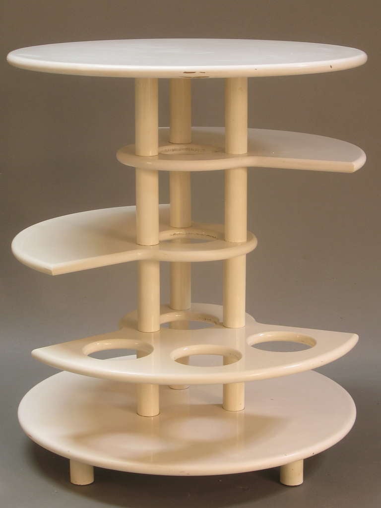 Round wooden table with original white paint. Multi-tiered (5 levels). One of the shelves is designed to hold up to three bottles. Ingenious and funky design. Great as a drinks table, but would also work well for plenty of other uses - as a  bedside
