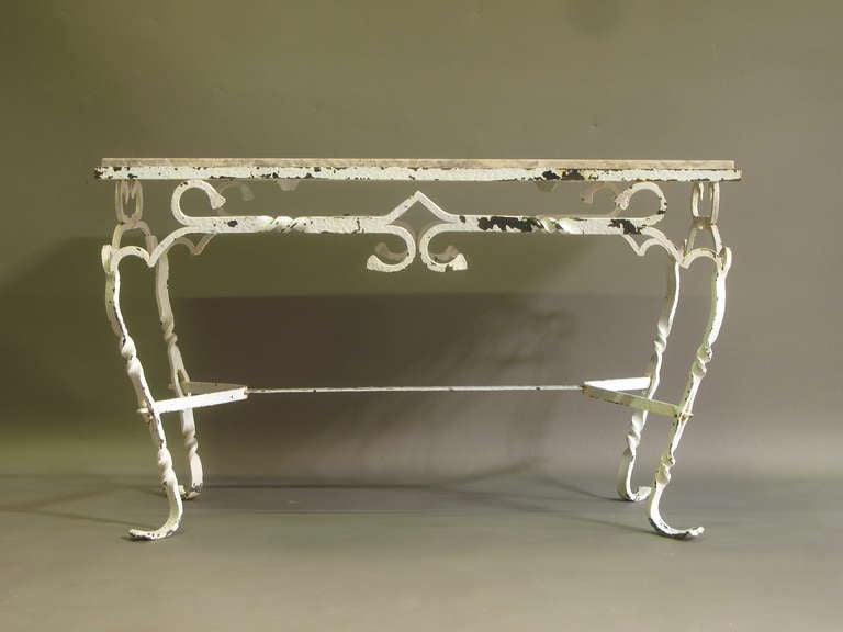 Lovely low table with a hand-wrought, hammered and twisted iron structure and a travertine top. Original white paint, traces of wear and age.