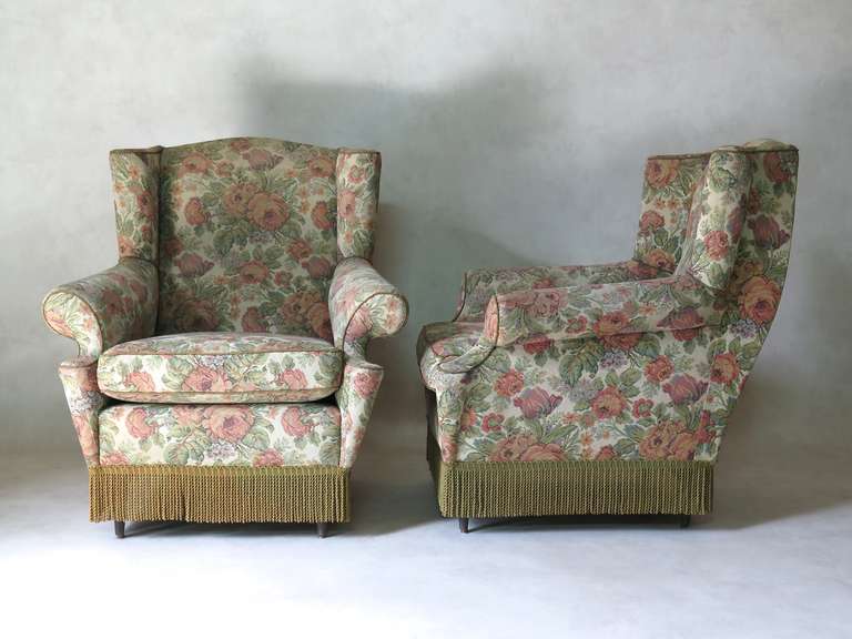 Pair of wingback armchairs, with cutaway armrests, and curving backs. Original upholstery.
