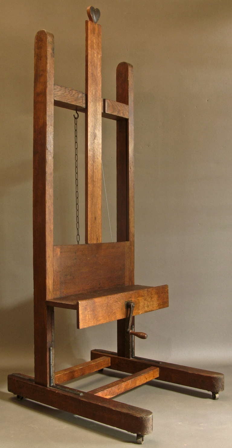 Solid oak easel, on casters. Height adjusts with a crank handle. Pulley system on back. Made by Parisian firm Hardy-Alan.