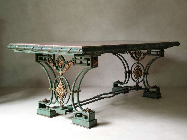 Finest quality large 1940s French Art Deco dining or center table. Heavy hand-wrought iron base, with original green patina, and gilt accents (acanthus leaf decor). Gilt ribbon detail on the table surround. The marble top is a thick slab (5