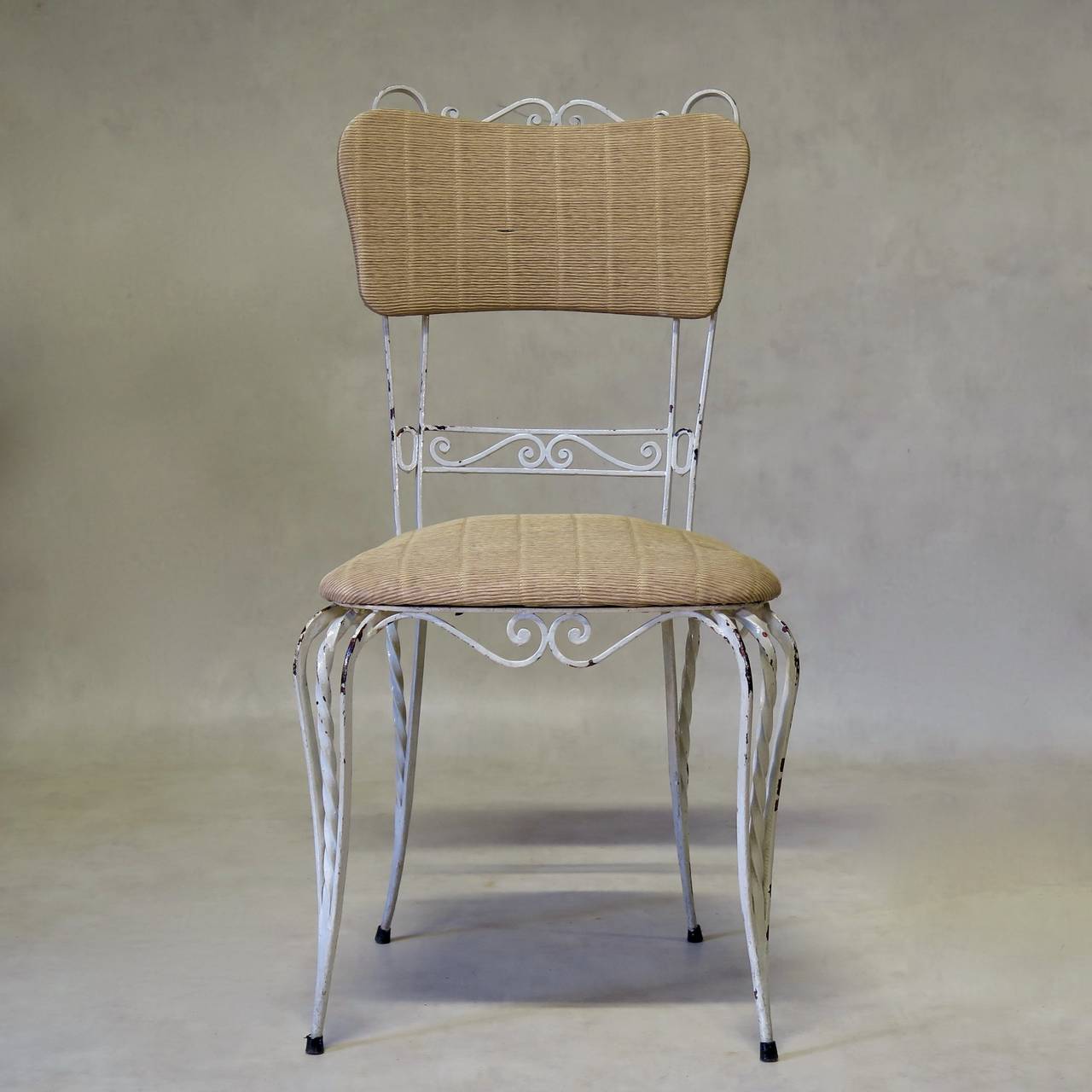 Charming set of three wrought iron chairs, the seats and backs upholstered in textured faux-straw vinyl.