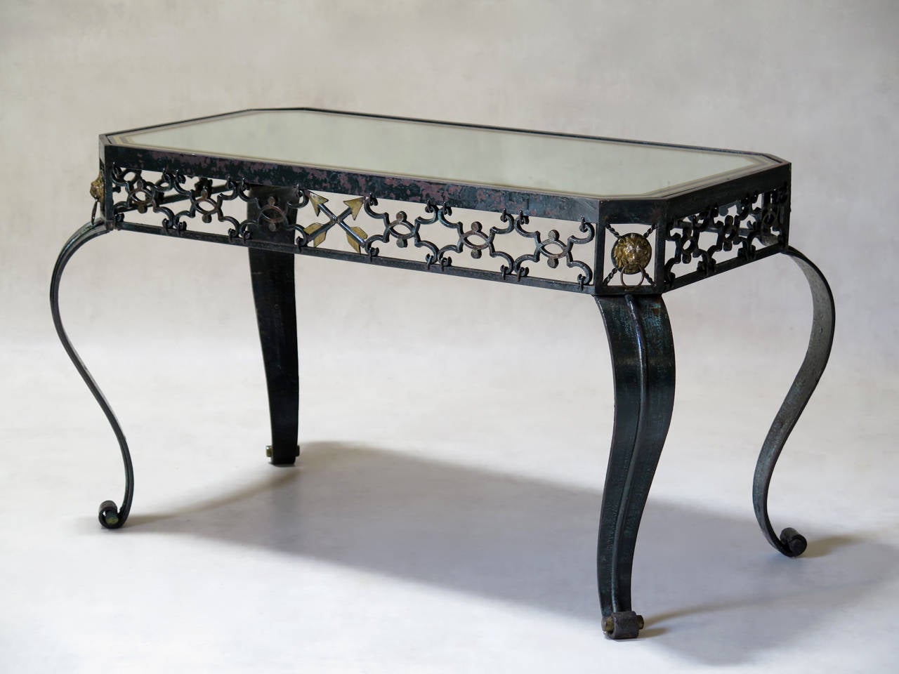 Chic trio of heavy, wrought iron coffee and side tables: two small round ones and one rectangular, painted dark green with gilt details. The two round tables have glass tops with mirrored borders; the rectangular table has a mirrored top with a