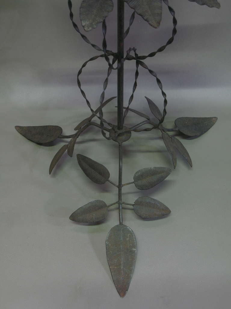 Charming floor lamp made of iron. From base to top: tripod leaf base, two twisted iron spheres, a leaf 