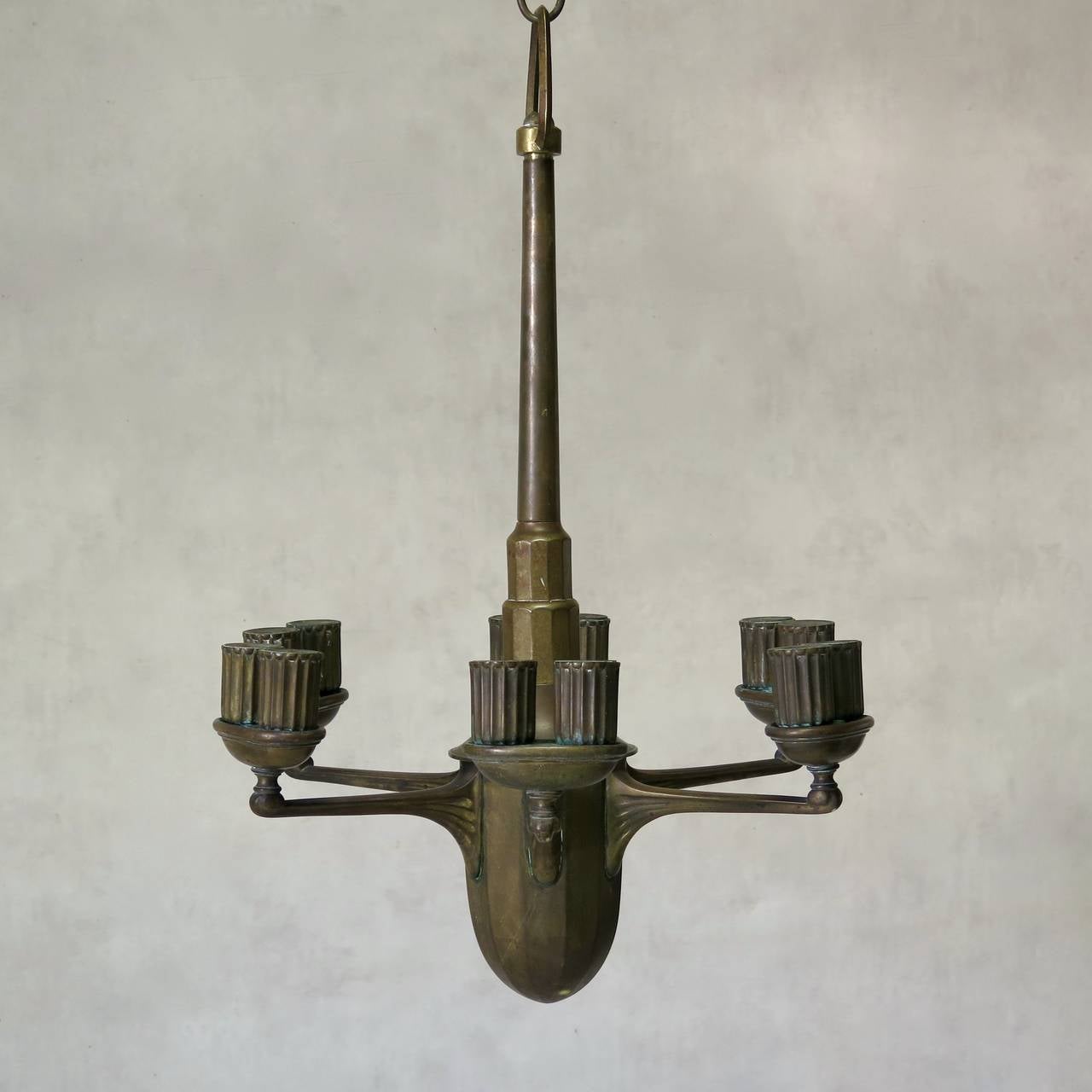 Elegant and heavy six-arm solid bronze chandelier with lovely lines, drawing on both Art Nouveau and Art Deco influences. Each arm supports an ovoid cup with two ridged light holders (the chandelier is meant for twelve lights). Stepped stem. Ovoid