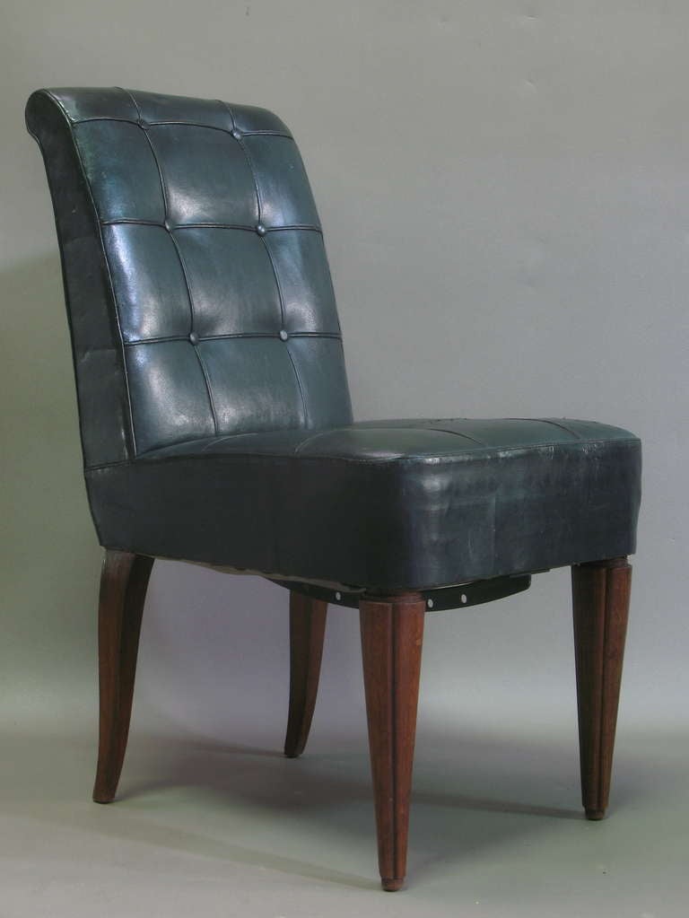 Set of six heavy and well-built dining chairs, upholstered in original dark green button-tufted leather. Cone-shaped front legs; very slightly splayed back legs. Deep and comfortable seats.

There is a curved iron rod with holes in it fixed under