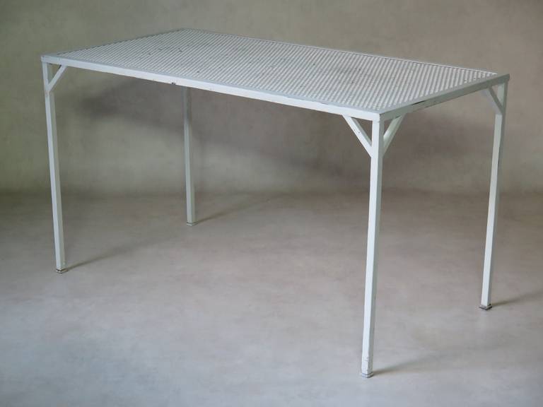 Rectangular table of simple, unfussy design, with a perforated sheet metal top rasied on square legs. Original glossy white paint finish.