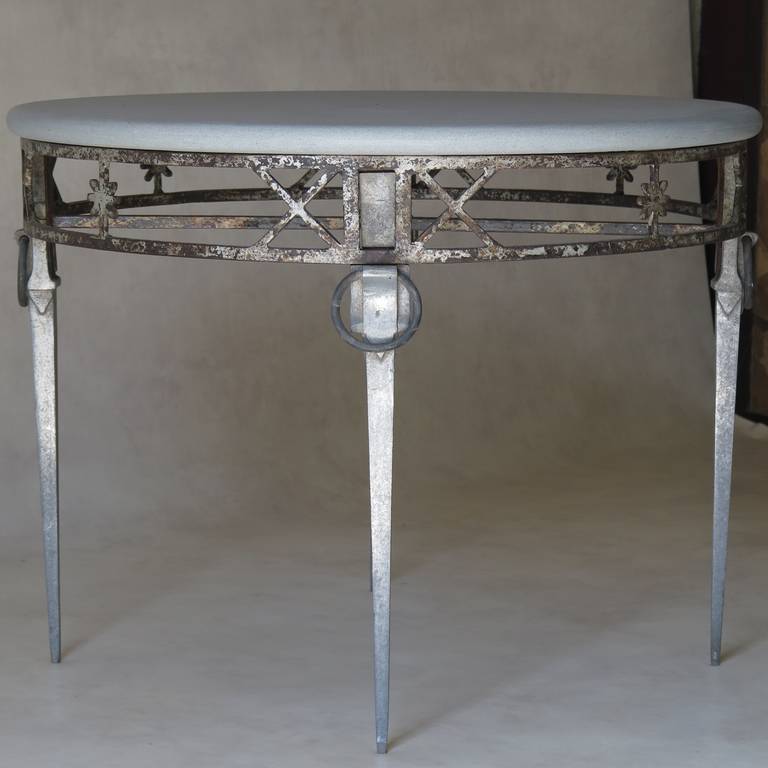 Rare and elegant Directoire style round coffee table. The table is raised on tapered cast aluminum legs with ring detail. The cast iron apron is adorned with X-shape and star motifs and has traces of original paint. Grey stone top. Unique piece. One