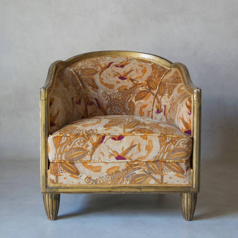 Stunning Art Deco set of two deep, barrel-back armchairs with a matching round side table. 
Giltwood. Newly re-upholstered in Art Deco period velvet fabric velvet, with an exotic floral and hummingbird motif.
The table top is also upholstered, and