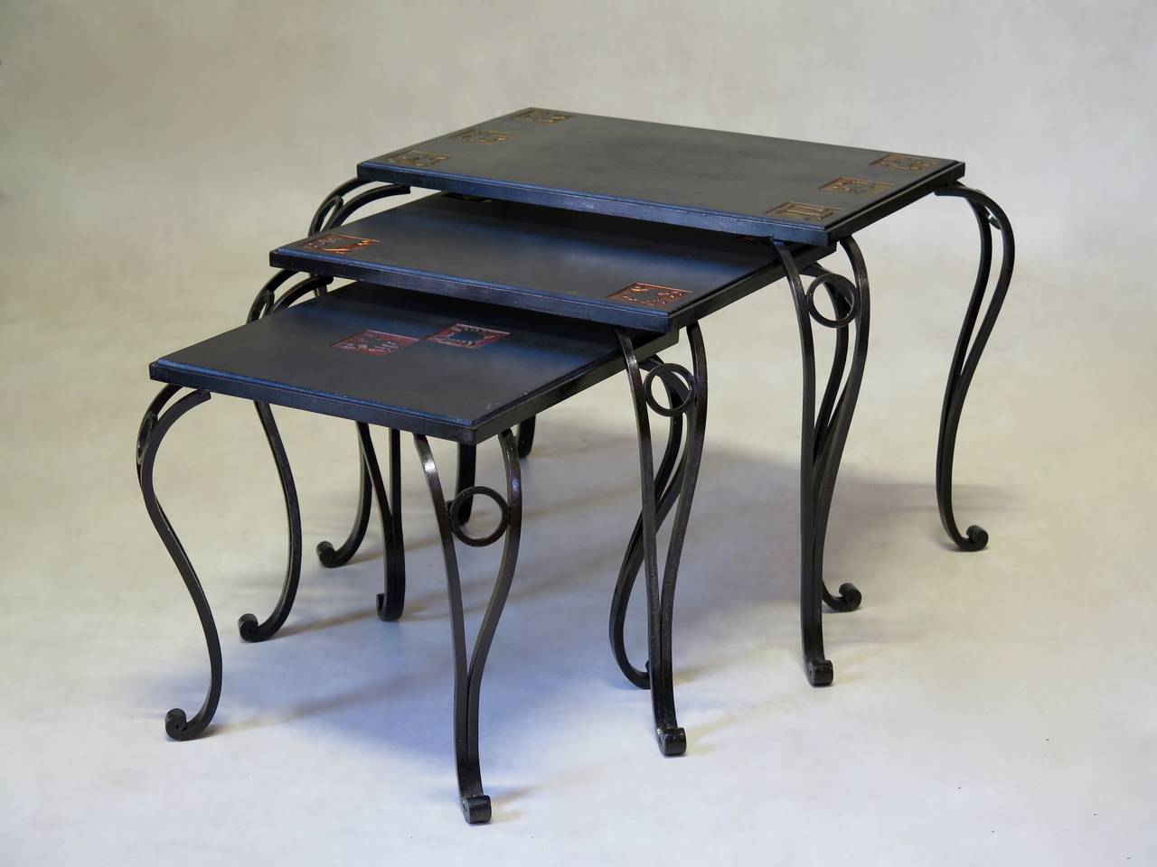 Fun and elegant set of three nesting tables. The slate tops are decorated with star-sign motifs, with yellow, orange and red backgrounds. Raised on wrought-iron cabriole legs.

Dimensions provided below are for the largest table.
