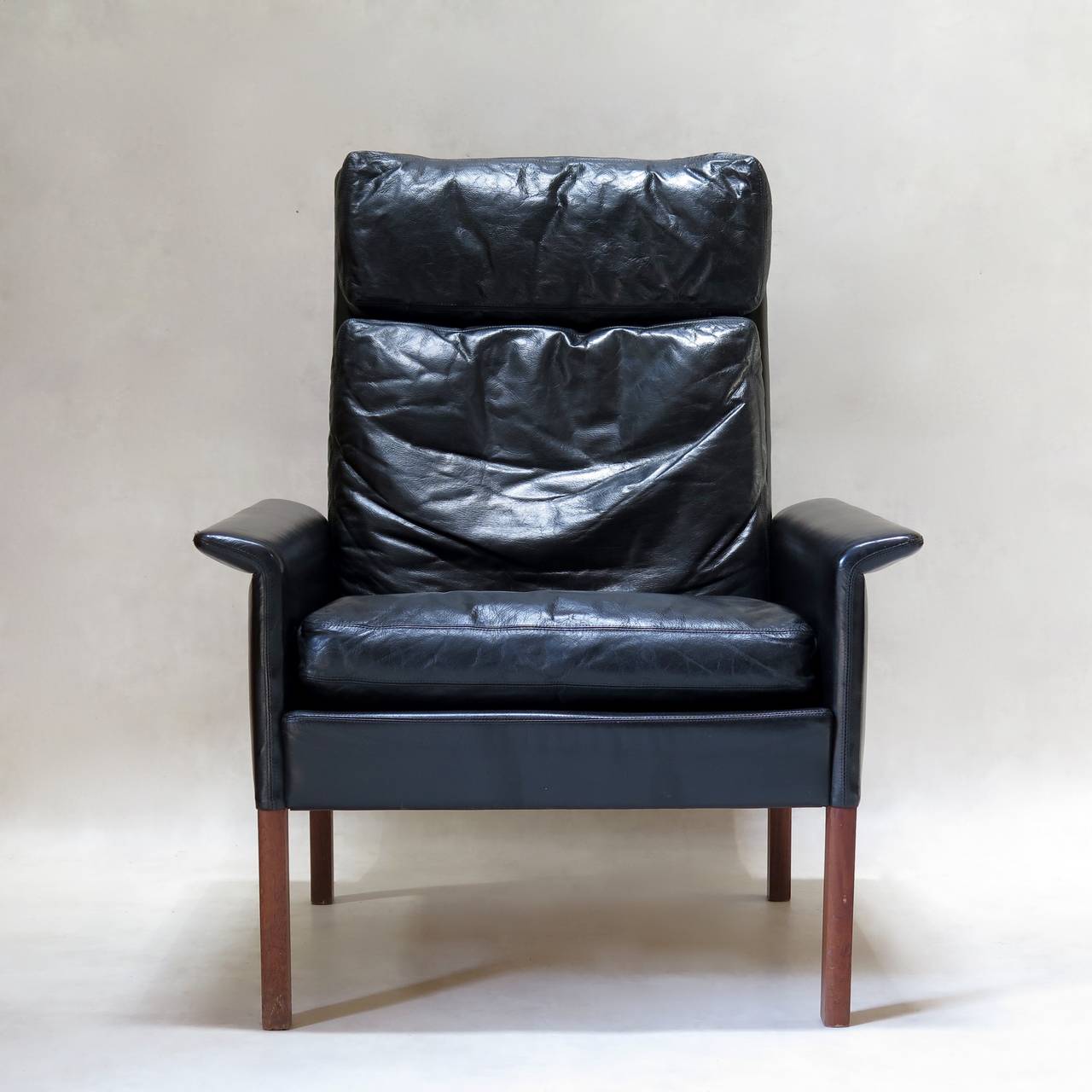 Handsome and comfortable pair of black leather-upholstered armchairs, with outwardly-turned armrests, raised on rosewood legs. 
Sleek design by Danish designer Hans Olsen for C.S. Møbler.
Stamped by the 