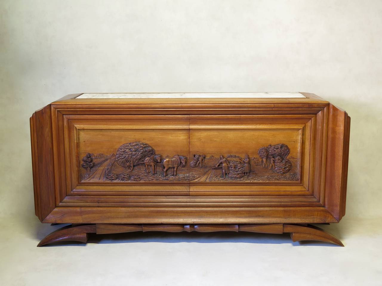 Spectacular and unusual large two-door sideboard. Mahogany and sculpted fruitwood doors. The base has a superb, very graphic line. The doors are elaborately carved in relief, representing an agricultural scene (wheat-harvesting in the fields). The