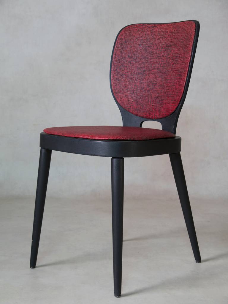 Set of wooden chairs, painted black. Seats and backs upholstered in red and black textured vinyl.

Approximately 14 available.