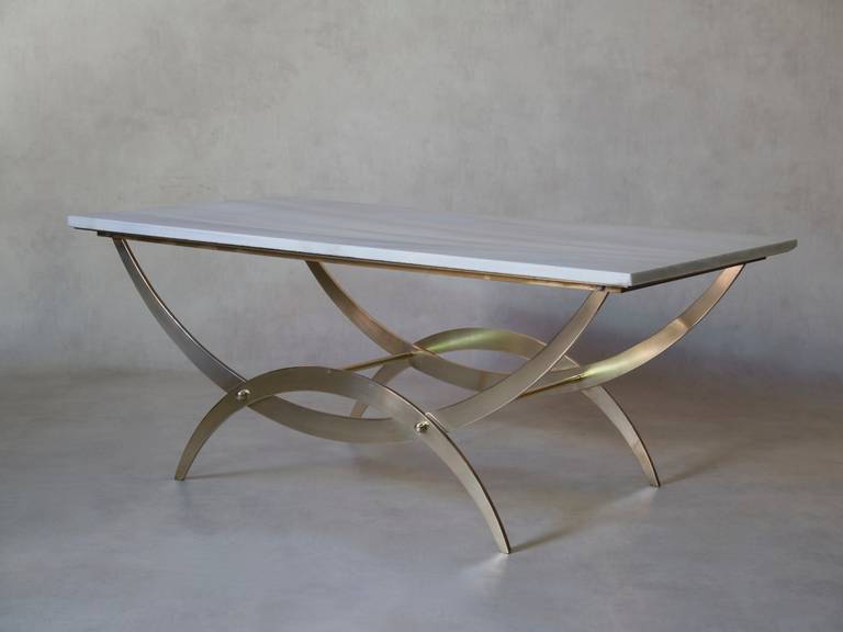 Table basse avec une base curule en laiton poli. Le plateau en marbre blanc est délicatement veiné de gris.