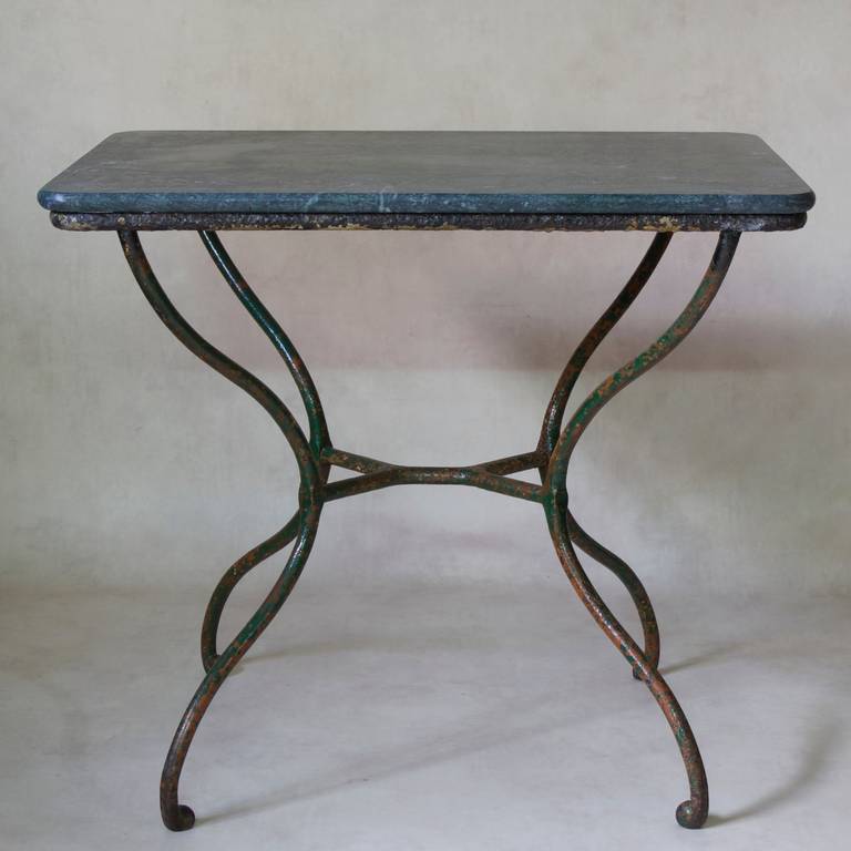 Charming side table with a shapely wrought-iron base. Traces of green and orange paint. Green stone top.