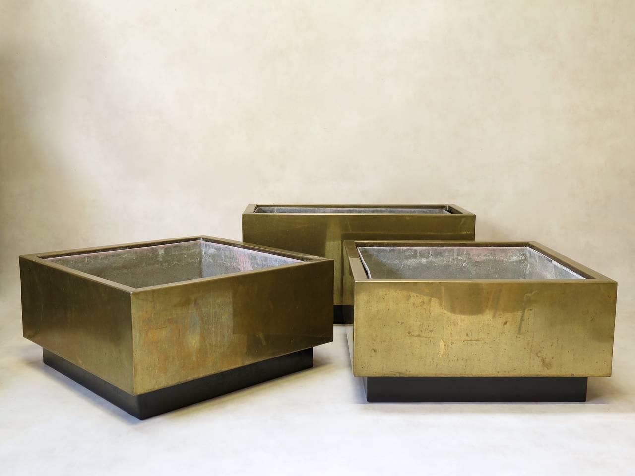 Chic set of two square brass jardinieres. Raised on a black-painted recessed metal base. The interiors are fitted with removable zinc linings.

