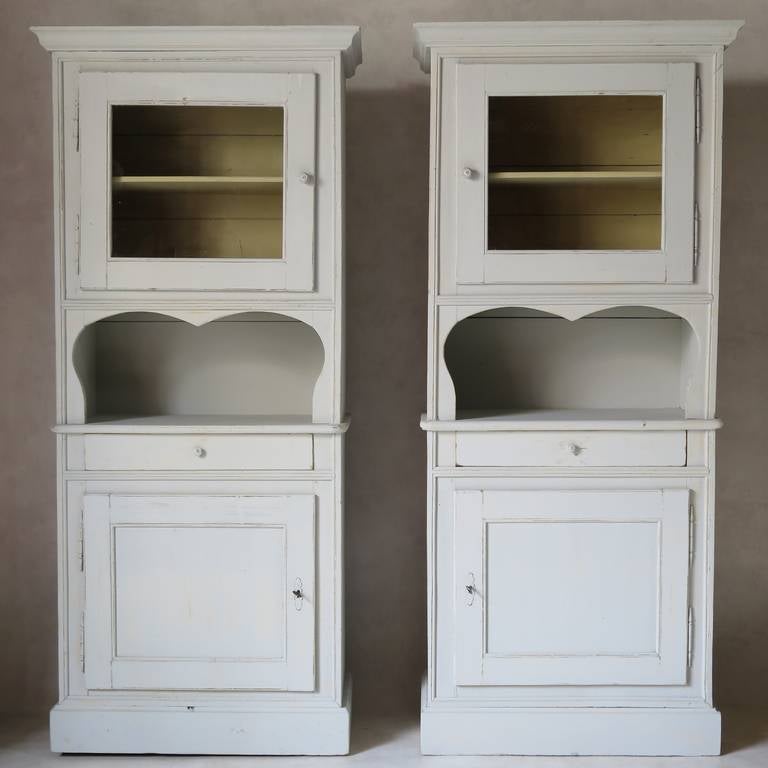 A very charming and unusual pair of pine cabinets, originally designed for the kitchen.
Each cabinet is composed of a top, glass-fronted display section; a central, open section decorated with a nice cut-out shape; below this, a drawer; and