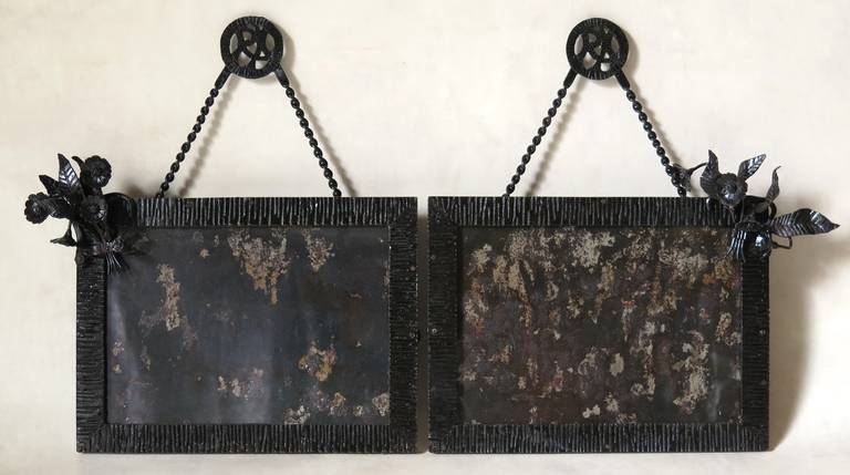 Une paire de cadres en fer forgé martelé, décorés de chaque côté d'un délicat bouquet de fleurs, également en fer forgé.

Monogrammé 