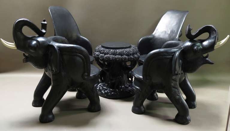 A wonderful and unusual set of two low and large armchairs, two high-backed chairs and a table, with elephant motif.

The backs of the chairs and barrel-shaped armchairs feature elephants' heads, complete with painted wooden tusks.

The table is
