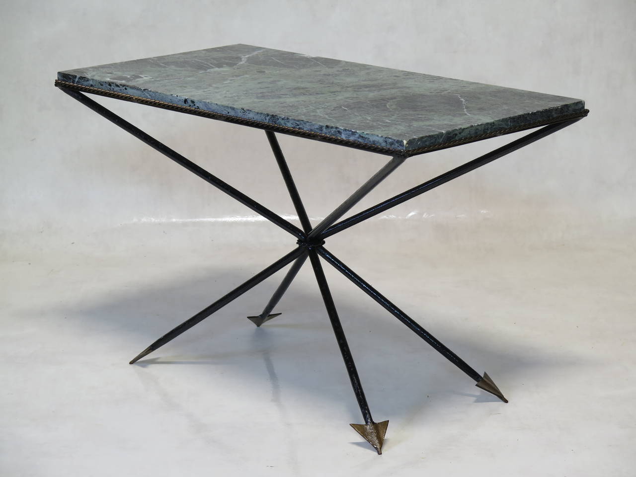 A chic wrought iron coffee table, painted a glossy black, with gilt arrow-heads and twisted rope detail on the table top surround.

The top is green marble, veined with black and white.