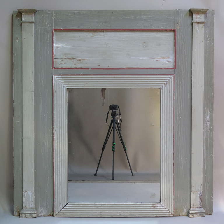 Simple and elegant trumeau/over mantle mirror. The wide frame painted dove-grey with details in contrasting lighter grey and red.  The mirror is antique, and set in a reeded frame, flanked by two slim columns.