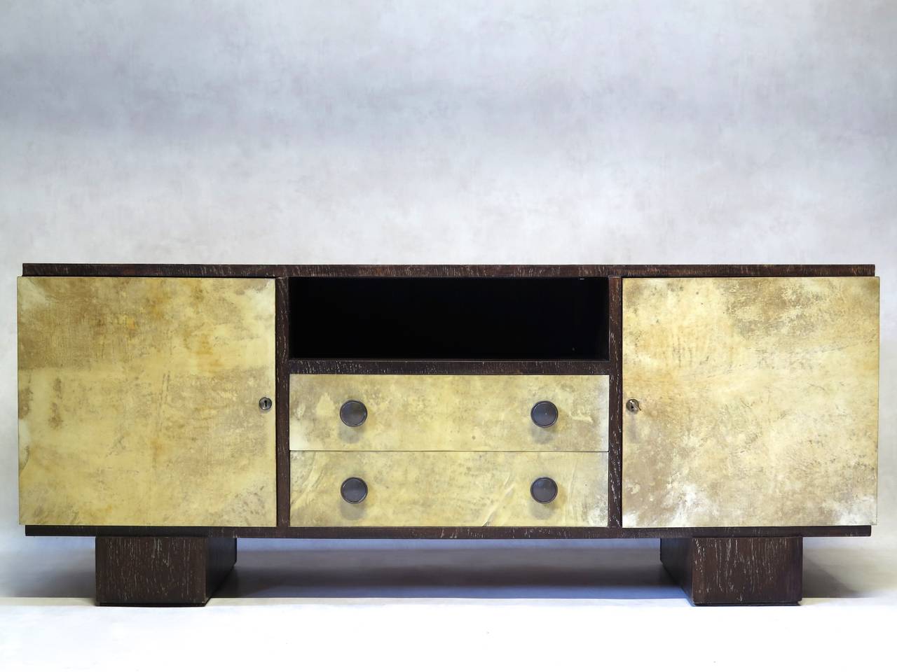 Elegant and chic sideboard made of dark oak with a cerused finish. The front doors and drawers are clad in parchment, with elegant brass key holes and drawer pulls.