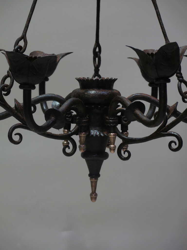 Lovely wrought iron chandelier. Both solid and elegant. Ends in acorn-shaped bronze finials. The lines are graceful, and the piece is very well-made.
