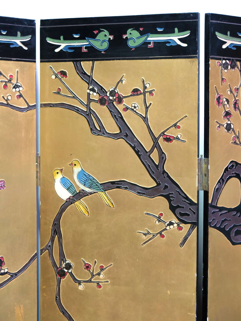 Beautiful coromandel screen. Lacquered in gold on one side and black on the other. Decorated with colorful birds, cherry blossom, bamboo, etc. The decor is raised on one side and etched on the other.

Dimensions provided below are for the screen