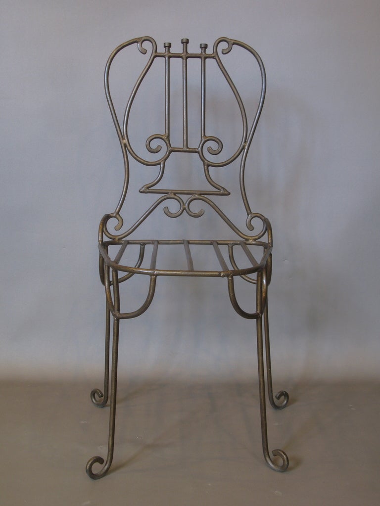 Interesting metal chair featuring a stylized lyre back and scrolling feet. Original bronze colour. Reminiscent of the work of French designer Marc Du Plantier.
