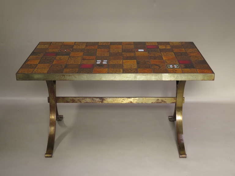 Funky mid-century dining or center table with a colourful glazed ceramic tiled top, in warm red, orange and brown tones, supported by an iron base.