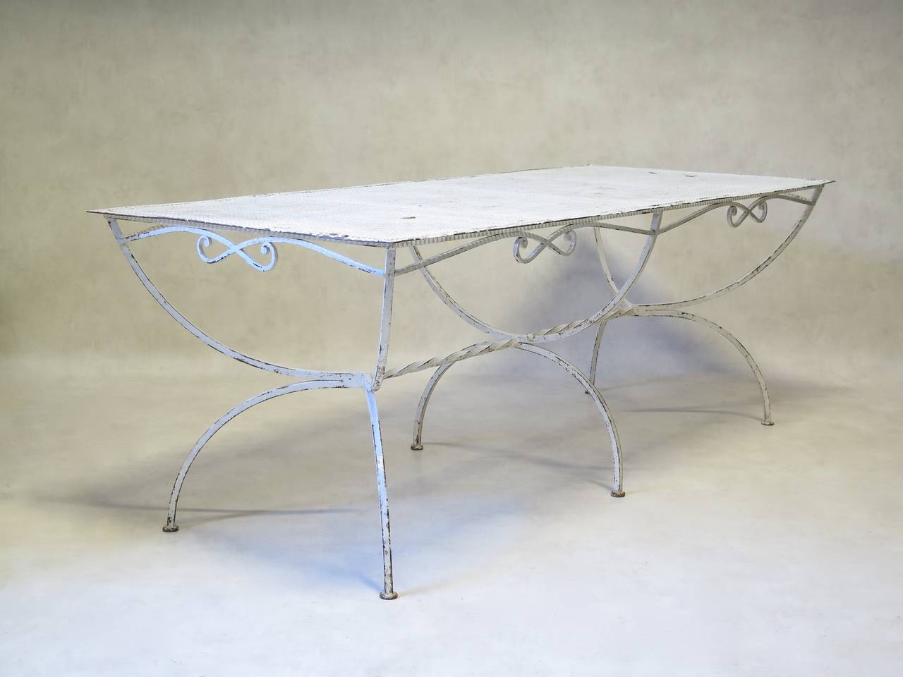 Large wrought iron, bow-motif painted garden or outdoor dining table. The top is made of cloverleaf-patterned sheet metal. Curule-style base, with a bow-motif apron and twisted iron stretcher.
Nice quality. Rare piece.