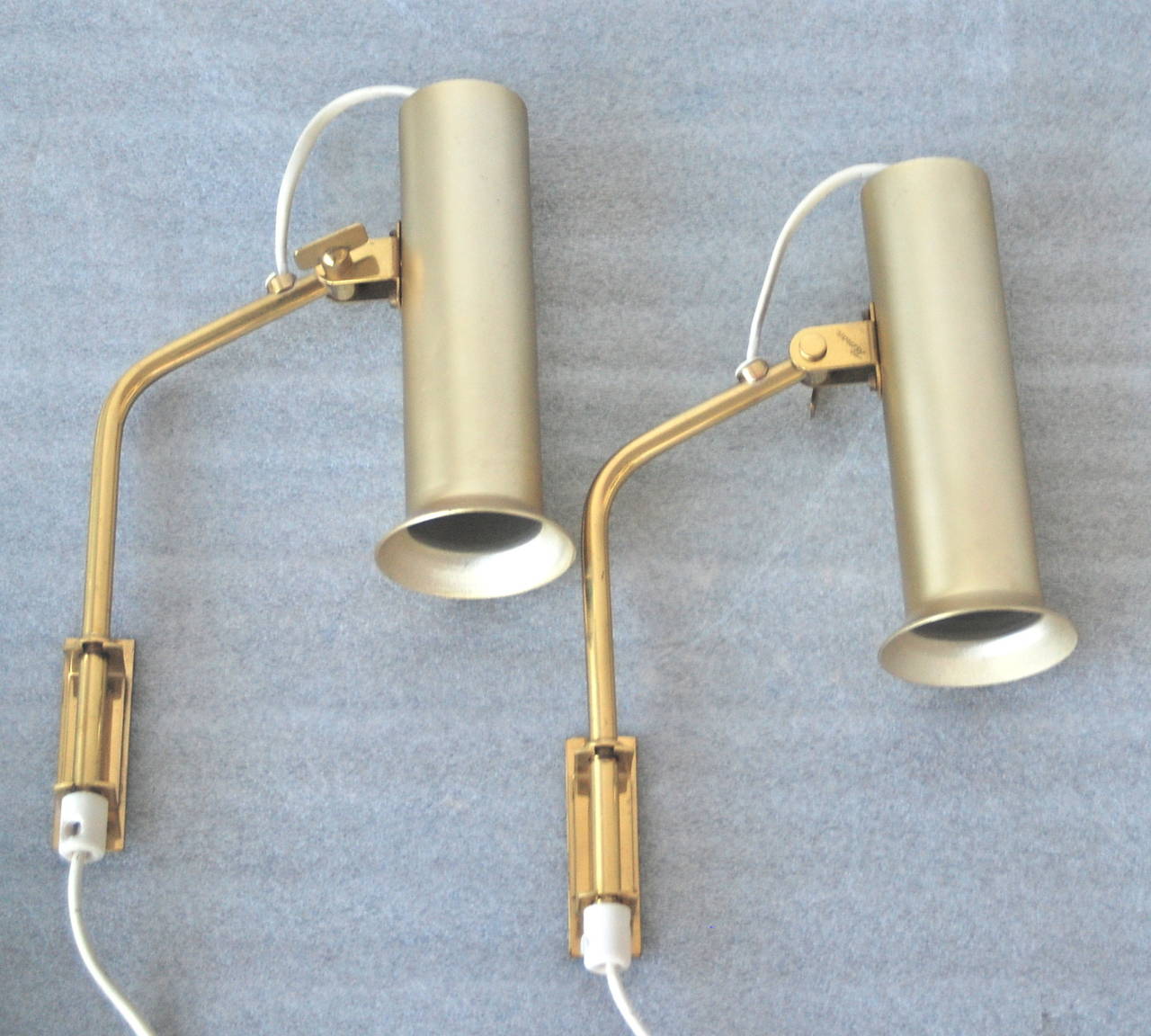 A pair of wall lamp manufactured by Idman, Finland, circa 1950s.
Design by Mauri almari.  Marked - Idman. Featured in Idman catalog number 143.
Adjustable, coated aluminum shades with polished brass arms on brackets.
Measures: Overall height 11