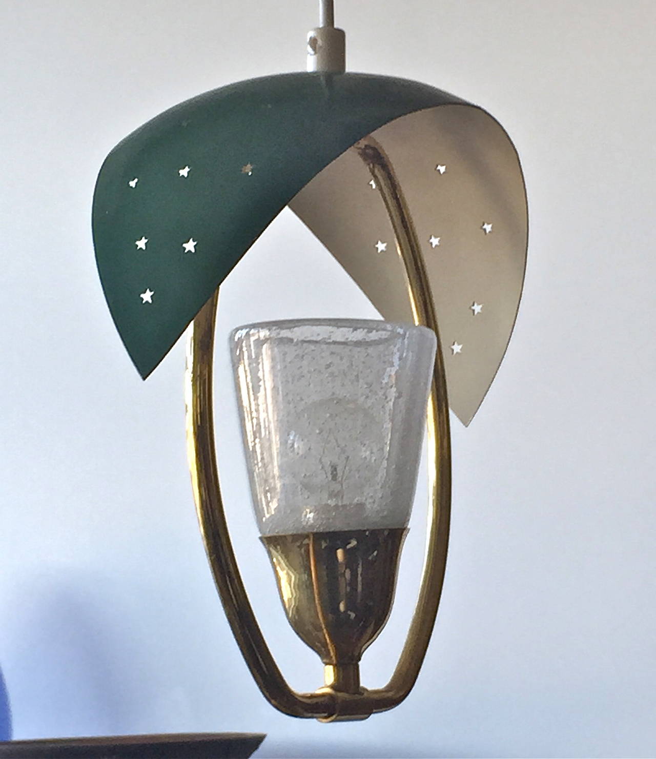 A pendant, by Valinte Oy, Finland, circa mid-20th century.
Perforated enameled shade, brass frame, glass lampshade.
H 11