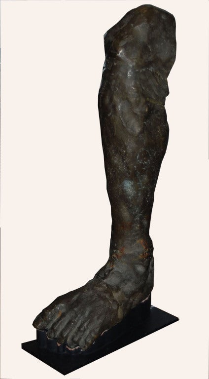 Une sculpture en bronze patiné (modèle de jambe d'homme) sur un piédestal personnalisé.