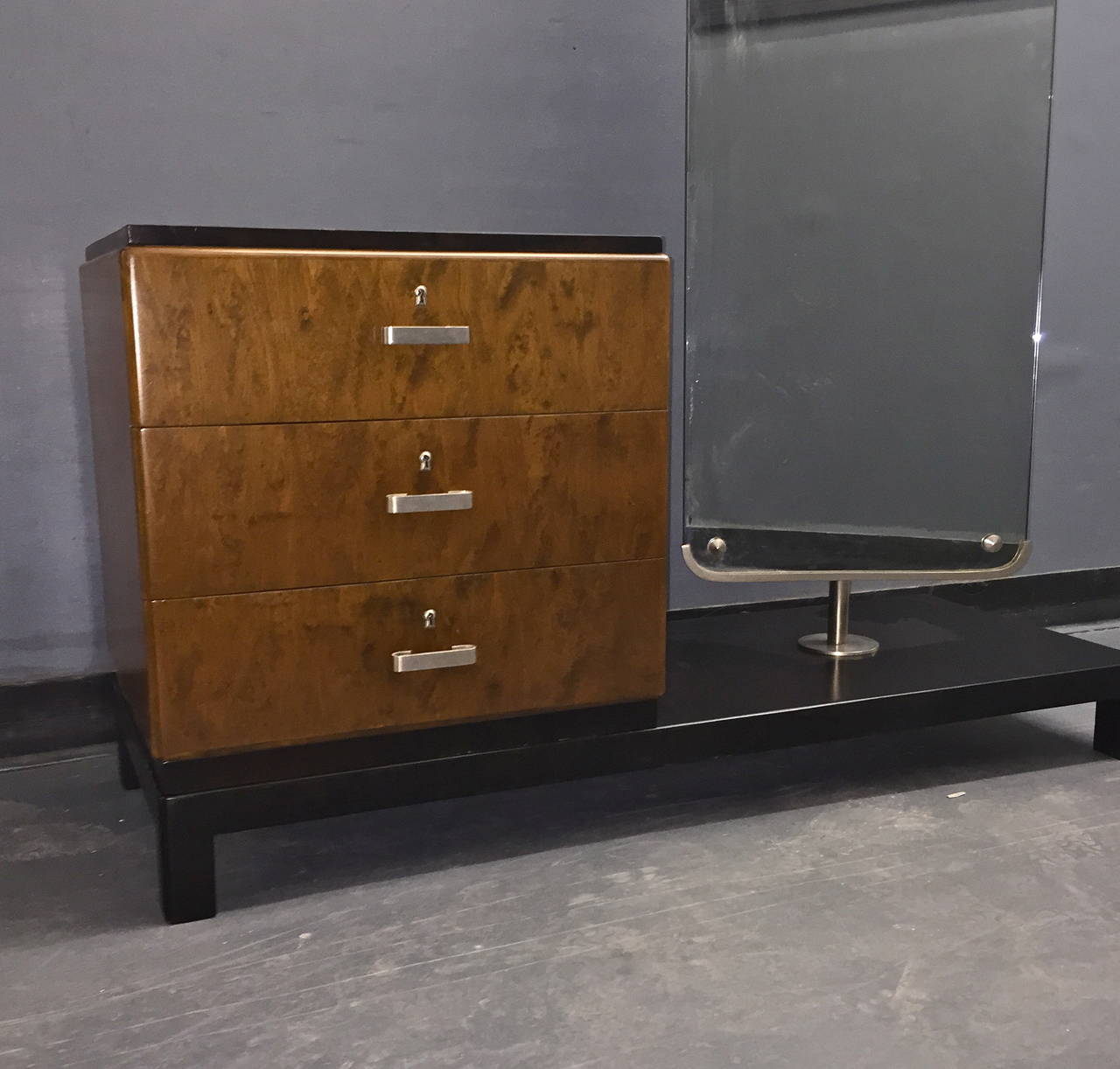 Dressing table with mirror designed by Axel Einar Hjorth for Nordiska Kompaniet, Sweden, circa 1930s.

Two-tone stained birch veneer finish and nickel-plated hardware. The original mirror is swivels 360 degrees. Three drawers, one key