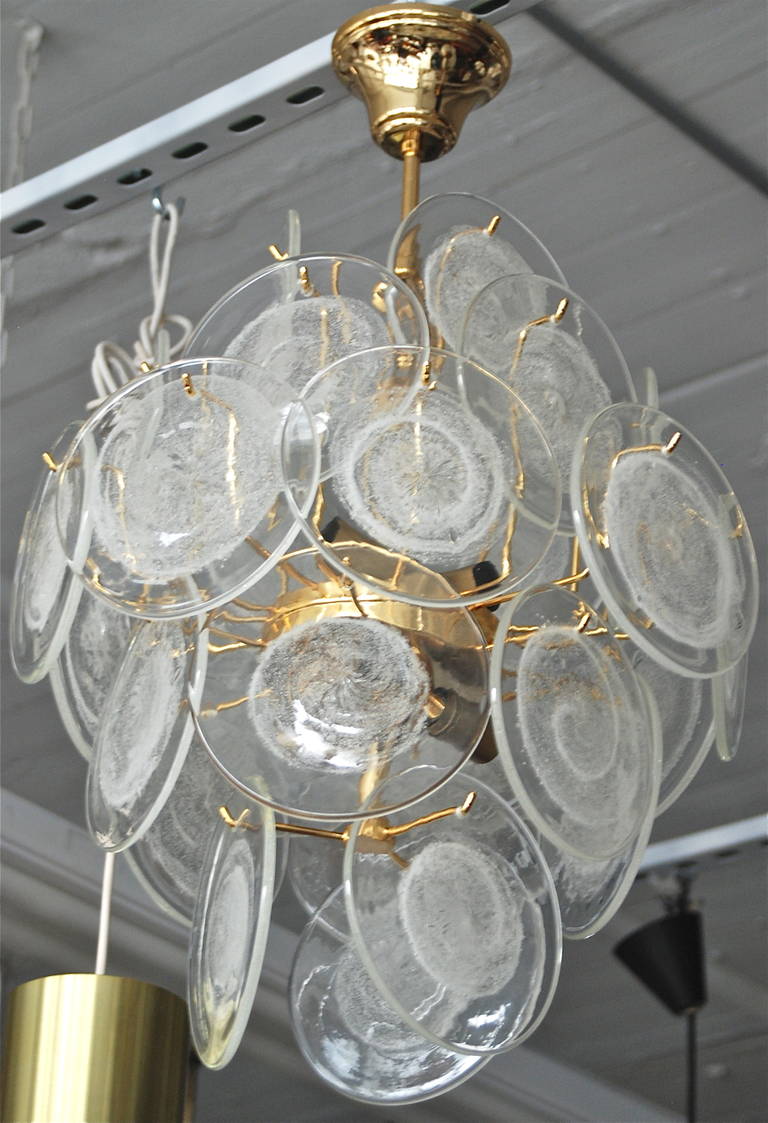 A Chandelier by Vistosi, Italy, Circa 1960th.
Brass frame chandelier with 27 hand made glass discs.
6 candelabra style sockets. Drop 27