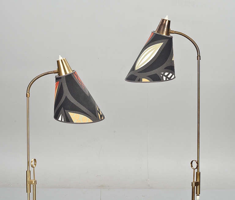 A pair of floor lamps produced by Falkenberg, Sweden, circa 1960. Brass hardware with fabric shades. Adjustable height 37