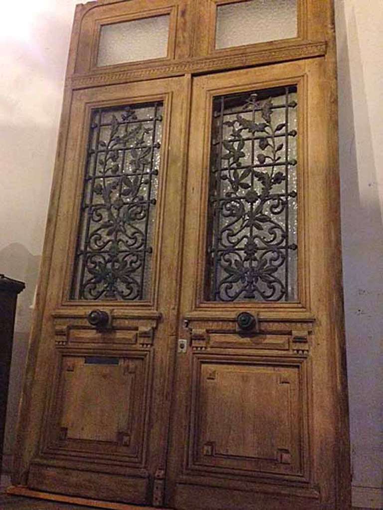 Antique Double Door with Transom
Beautiful antique double doors featuring floral and grid ironwork in front of opaque window glass, and a transom with two square opaque glass windows.