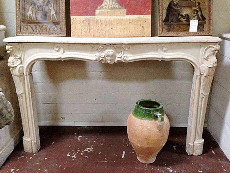 A lovely French limestone mantel featuring reverse fluting and scroll like designs on the legs and lentil leading up to a beautiful medallion. 
Firebox measurements: 60 1/4