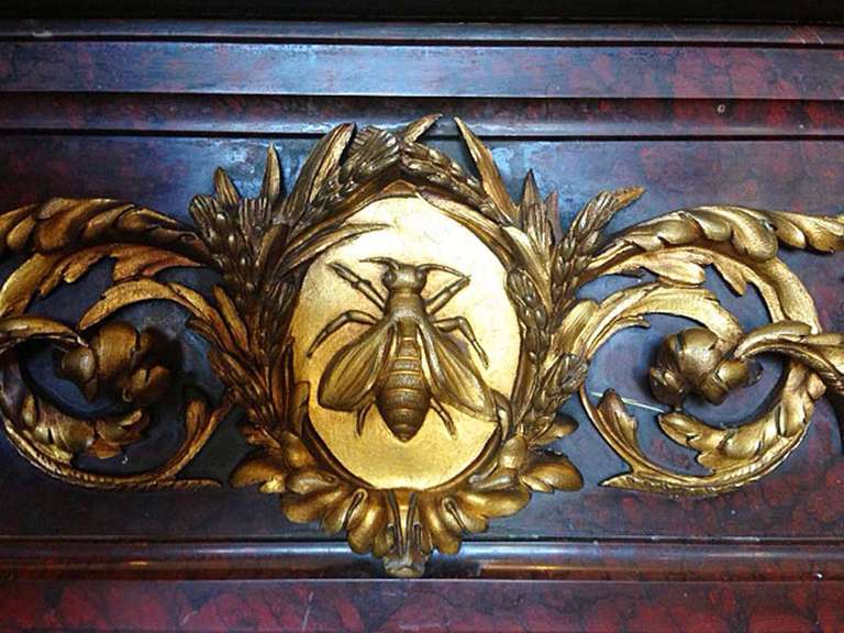 From the Office of the Minister of Culture in Belgium, we have this deep red with black veins marble mantel. 18K gold plated bronze embellishments adorn this piece, as well as a bee decor medallion.