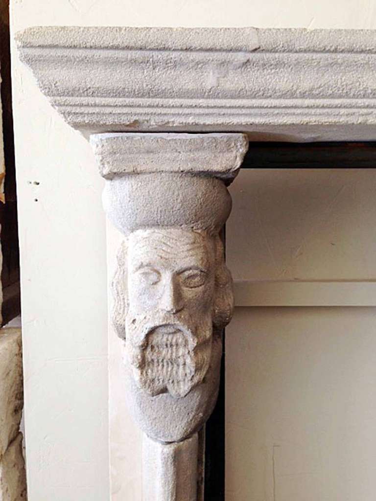 This high stone Gothic style mantel is a unique piece in our collection. The legs are crowned by two faces, one being a bearded man and the other a woman.
Firebox measurements:  47 1/2