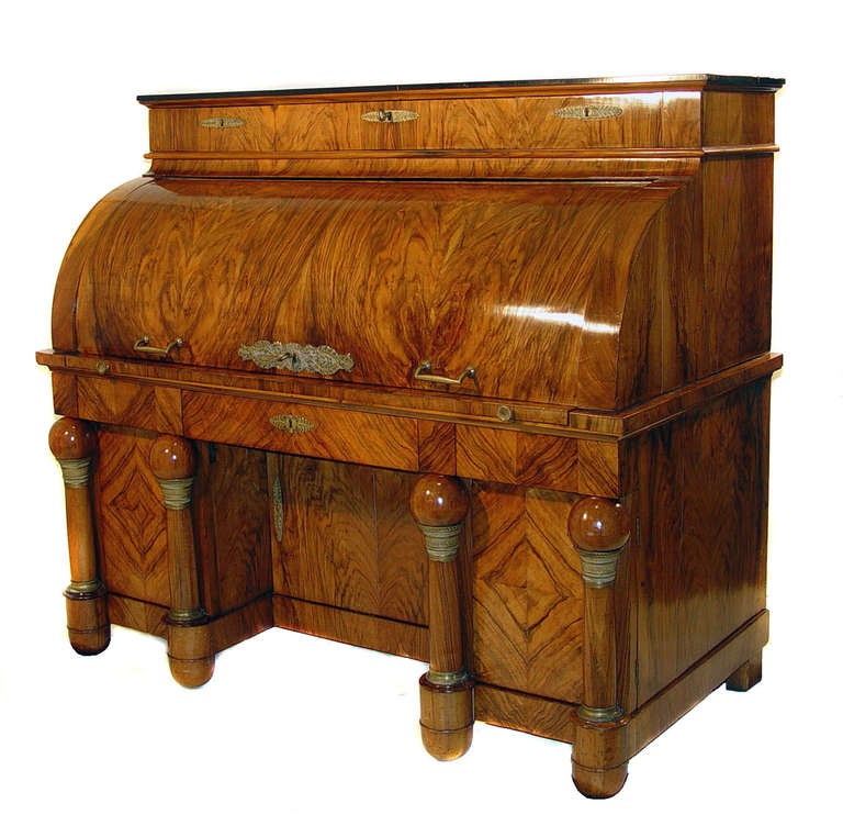 A rectangular ebonized top over three drawers above the cylindre which opens to reveal three drawers on either side of a document well, the well inlaid with a chess board pattern and augmented with classical columns and having five pigeon holes at