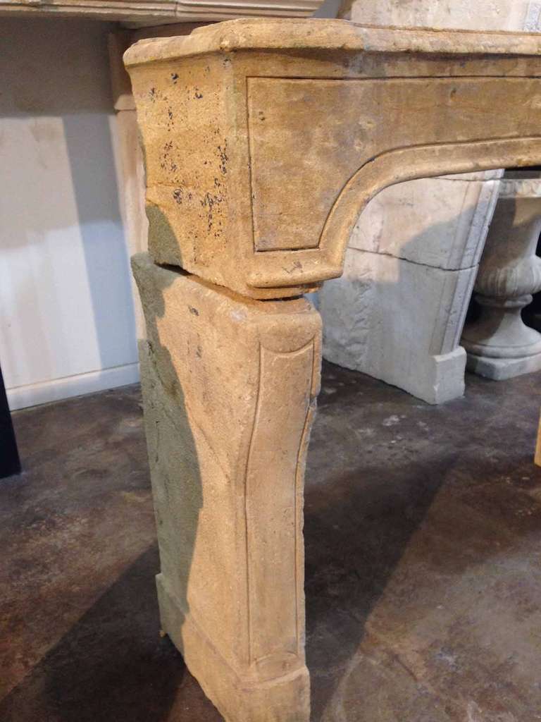 This antique mantel is made from smooth limestone, giving it an almost travertine feel. The lintel and legs both have an outline carving giving this piece a clean smooth look. 
Firebox: 38 1/2