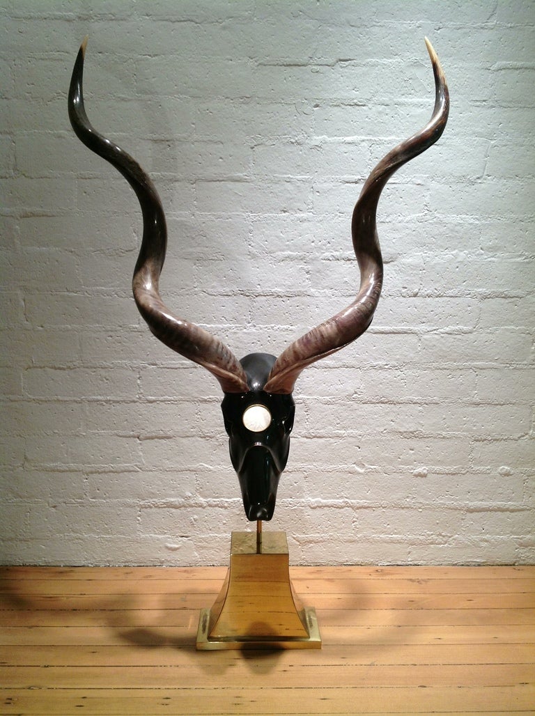 This Sculpture appears to be a Kudo Skull  that has been covered with resin, then  lacquered in black with brass inlay.
The horns extend 34