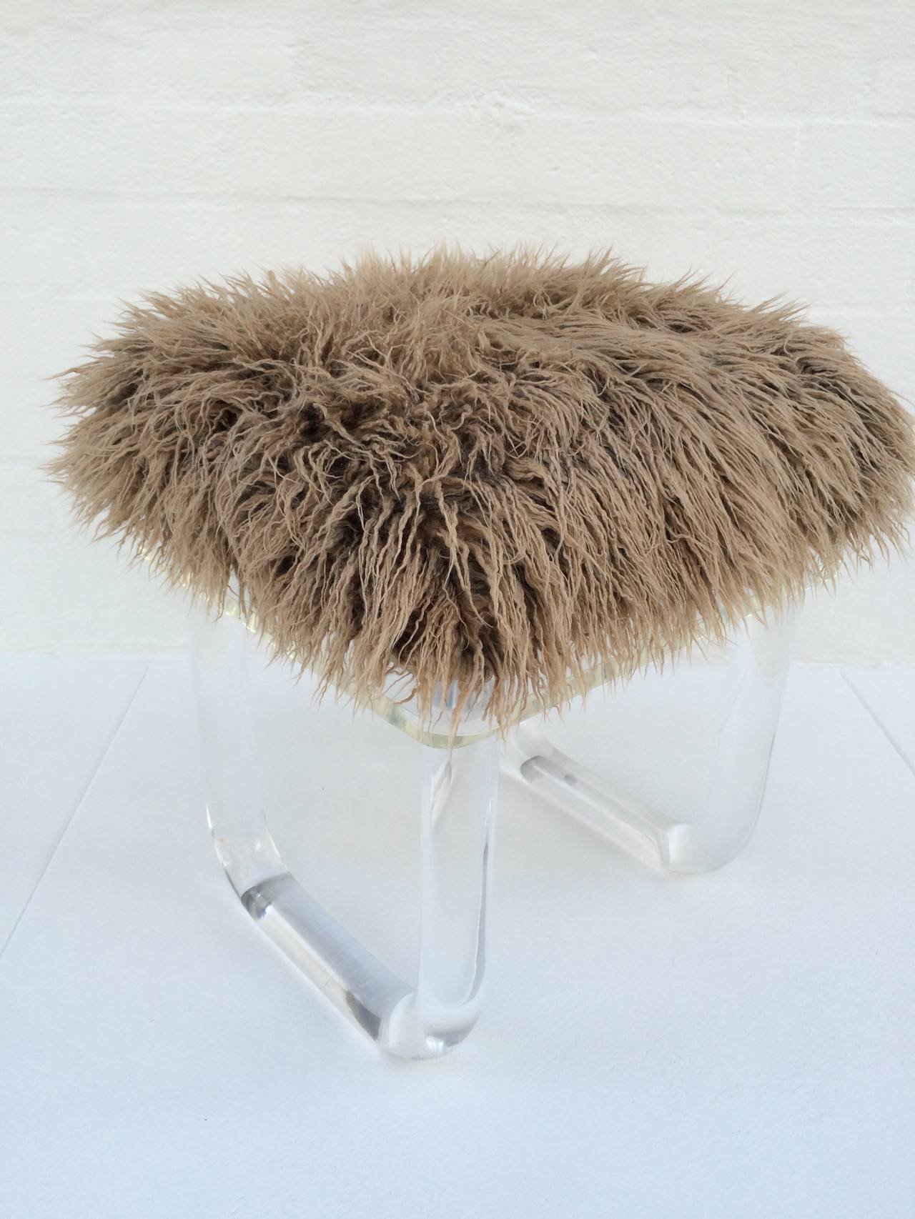 This fun and sexy vanity stool is all acrylic with thick heavy legs and a swivel top that is covered in a faux Mongolian lamb.