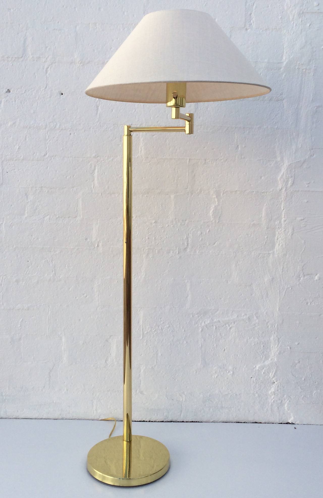 A adjustable polished brass floor lamp designed by Walter Von Nessen, circa 1970s. 
Adjusts up and down with the arm swinging forward and back. 
Newly rewired and professionally polished. 
New linen shade.