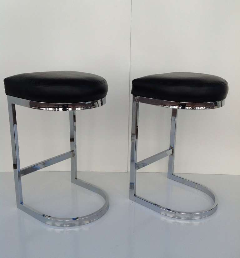 A pair of polished chrome cantilevered bar stools with the original black stitched vinyl designed by Milo Baughman dated 1978